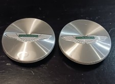 PAIR OF GENUINE ASTON MARTIN WHEEL CENTRE BADGES SILVER WITH GREEN WINGS EMBLEM 