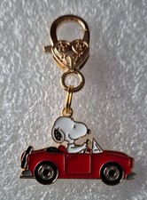 A snoopy in a red car on a Gold Coloured large Lobster  Clasp. 