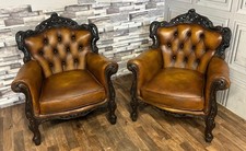 A pair of antique tan leather chesterfield rococo chairs in antique saddle tan 