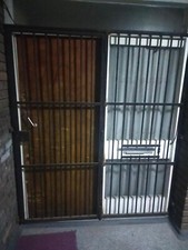Security large metal grill door covers the entire gate, black colour, used