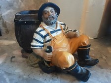 Fisherman sat next to a barrel
