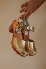 Heeled wooden clogs of natural leather with closed toe uppers on high heel