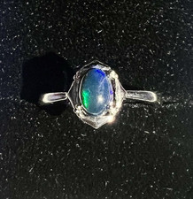 Small oval shaped black fire opal stone on a silver ring 