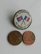 A VINTAGE METAL BADGE w/ TWIN FLAGS, TO COMMEMORATE 50 YEARS of PEACE.