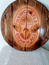 A Circular Newcastle Brown Ale Logo On Wood with a gloss lacquer finish.
