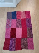 Knitted patchwork cot blanket in pinks and reds