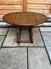 A small oval oak drop leaf coffee table with attractively turned legs.