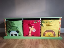 green toy storage unit with 3 compartments with jungle themed animals on it.