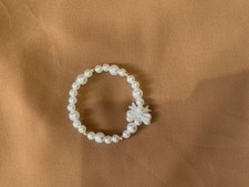 Elegant faux pearl bracelet with golden beads and a charming pearl bow accent.