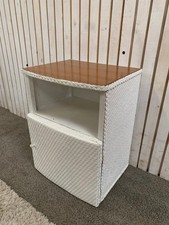 Small white bedside cabinet with one door in a Lloyd Loom style.