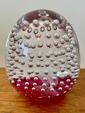 Egg-shaped glass paperweight with mass of controlled bubbles, clear w/ red/pink
