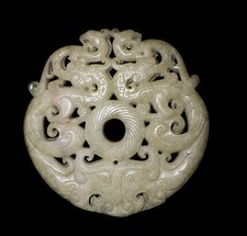 A white jade intricately carved Chinese amulet on a custom wooden base
