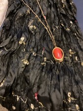 A Long Black Scarf With Small Flowers On And A Necklace with An Orange Stone