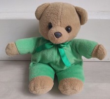 light brown teddy bear wearing green jump suit and green bow, 25cm tall