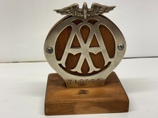 VINTAGE AA BADGE MOUNTED ON A WOODEN STAND.