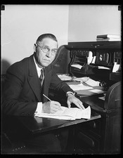 Photo:Man in Office Writing at