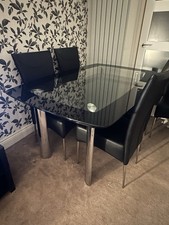 Harveys glass boat dining table with 6 black chairs