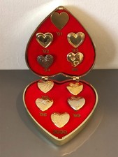 Heart-shaped box of 10 Variety Club International gold-coloured badges 1991-2000
