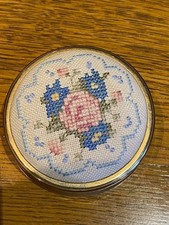 A vintage trinket box with an embroidered top in gold coloured metal and lined