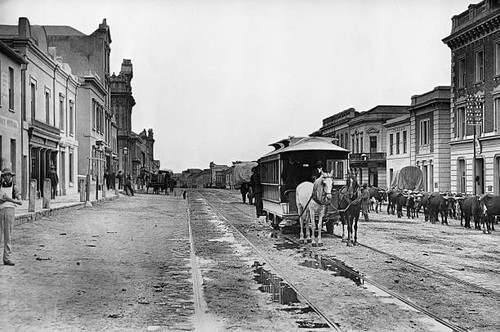 Horses pull streetcar along - a,