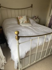 Beautiful cast iron bedframe with brass rails around a base and mattress, m & s 