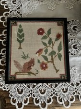 Antique framed needlepoint sampler with floral and animal motifs.