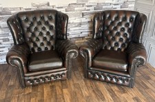 A pair of antique brown leather chesterfield  wing back chairs 