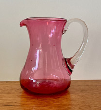 Small cranberry glass jug with clear handle, likely Victorian/antique