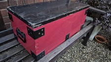 Old wooden chest with metal banding painted red and black.