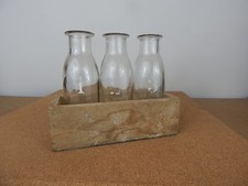 3 Small Childrens Milk bottles numbered 1.2.3 in wooden trough .