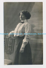 C013450 A woman in a blouse and skirt is standing next to a chair. Hudson Studio